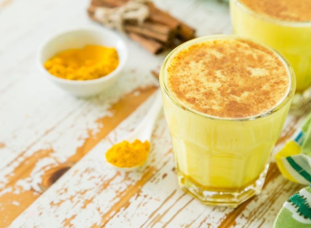 golden-milk-turmeric-tea-in-glass-on-wooden-table